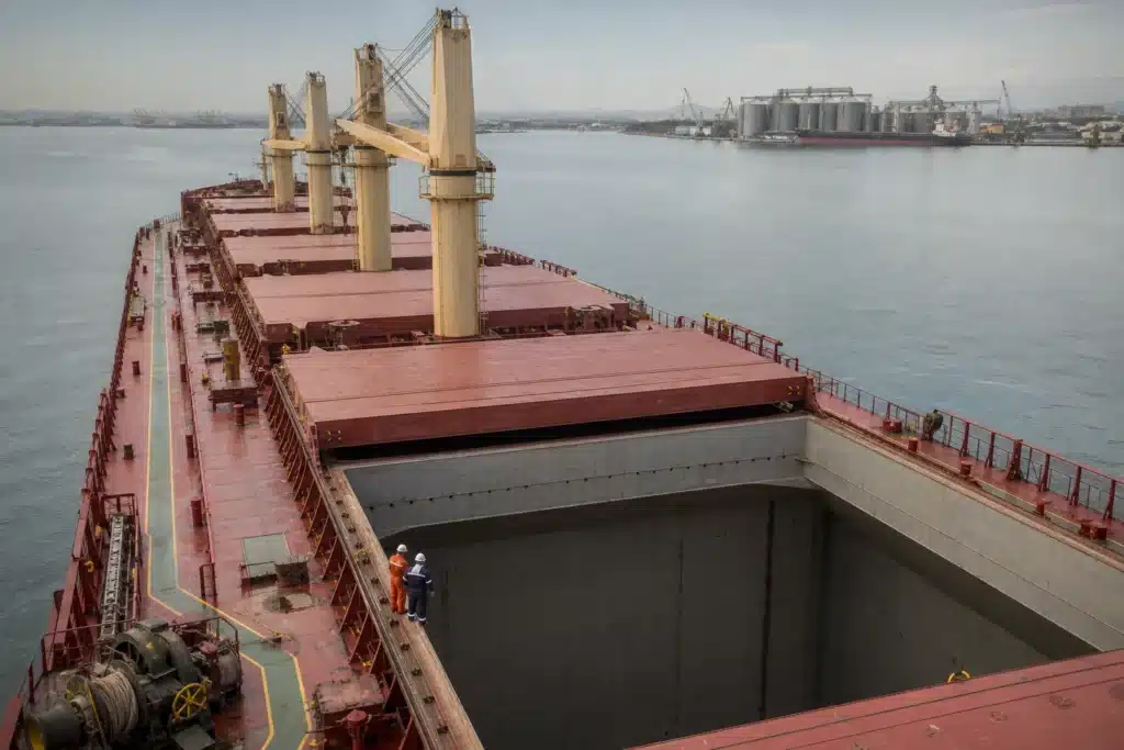 Crew members inspect a clean empty cargo hold aboard a Handysize bulk carrier before grain loading and berthing.