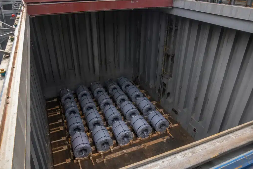 Steel coils correctly stowed on timber dunnage and chocks deep inside a dry cargo hold.
